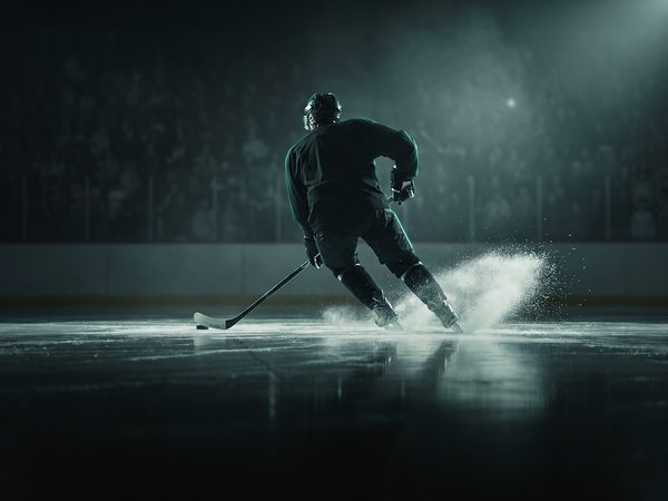 Ice hockey player carving a turn with ice spray