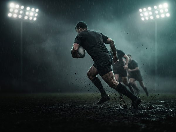 Rugby player carrying the ball through the rain